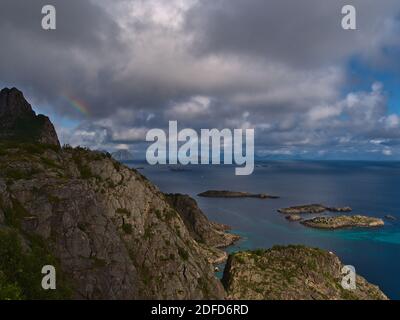 Schöne Luftpanorama der Küste des Norwegischen Meeres auf der Insel Austvågøya bei Henningsvær, Lofoten, Norwegen mit schroffen Bergen und Regenbogen. Stockfoto