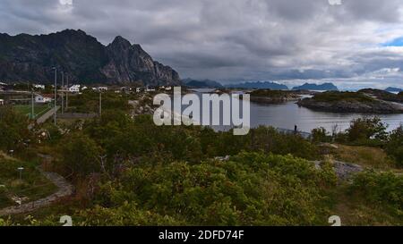 Schöne Aussicht auf die zerklüfteten Berge an der Küste der Insel Austvågøya, Lofoten, Norwegen mit Fischerdorf Henningsvær, Fußballplatz und Häusern. Stockfoto