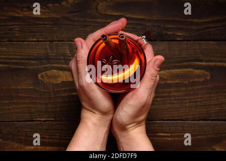 Glas Glühwein in Frauenhand auf dunklem Holz Tabelle Stockfoto