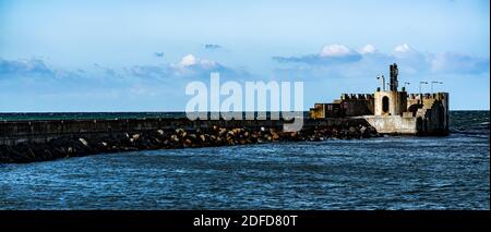 Langer Pier aus Beton und Felsen, der einen großen Hafen vor Stürmen und Wellen schützt. Stockfoto