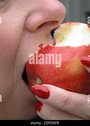 Frau, die einen Bissen von einem roten leckeren Apfel nimmt Stockfoto