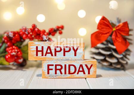 Happy Friday Wort auf Holzblock geschrieben. Happy Friday Text auf dem Tisch auf einem Hintergrund von Lichtern Stockfoto