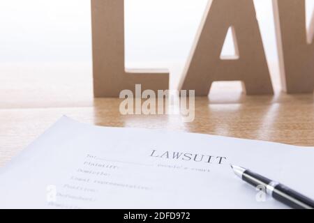 Eine selektive Aufnahme eines Dokuments der Klage Und Wort 'Gesetz' aus Holzbuchstaben auf dem Hintergrund Stockfoto