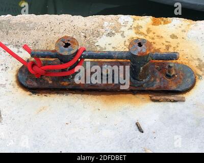Rostiger Poller mit rotem Seil Stockfoto