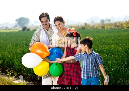 Glückliche indische Familie von Landwirt mit Ballons in landwirtschaftlichen Bereich Stockfoto
