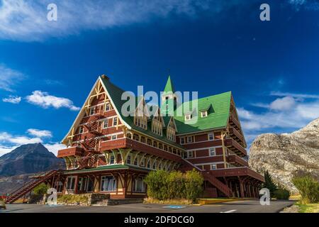 Prince of Wales Hotel im Herbst sonnigen Tag Morgen. Blauer Himmel, weiße Wolken über Bergen im Hintergrund. Wahrzeichen im Waterton Lakes National Park Stockfoto