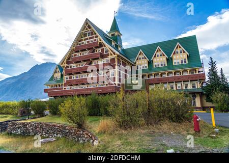 Prince of Wales Hotel im Herbst sonnigen Tag Morgen. Blauer Himmel, weiße Wolken über Bergen im Hintergrund. Wahrzeichen im Waterton Lakes National Park Stockfoto