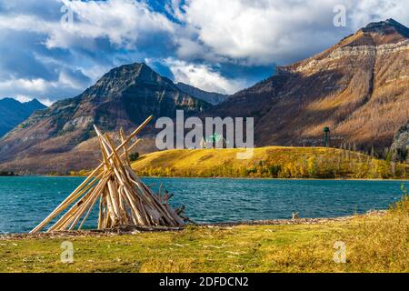 Driftwood Beach, Middle Waterton Lake Seeufer im Herbst Laubsaison Morgen. Blauer Himmel, weiße Wolken über Bergen im Hintergrund. Wahrzeichen i Stockfoto