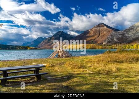 Driftwood Beach, Middle Waterton Lake Seeufer im Herbst Laubsaison Morgen. Blauer Himmel, weiße Wolken über Bergen im Hintergrund. Wahrzeichen i Stockfoto