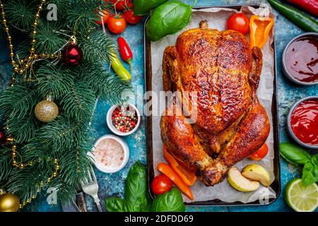 Gebratenes Huhn mit einer goldenen Kruste mit Gemüse auf einem blauen Hintergrund, Ansicht von oben Stockfoto