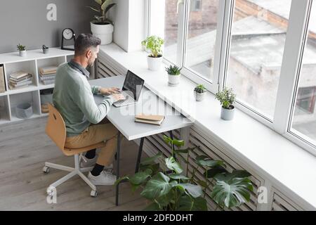 Computerprogrammierer, der an seinem Arbeitsplatz sitzt, der auf Laptop innen tippt Geräumiges Büro Stockfoto