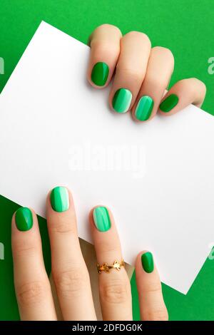 Womans Hände mit trendigen grünen Maniküre halten Postkarte Stockfoto