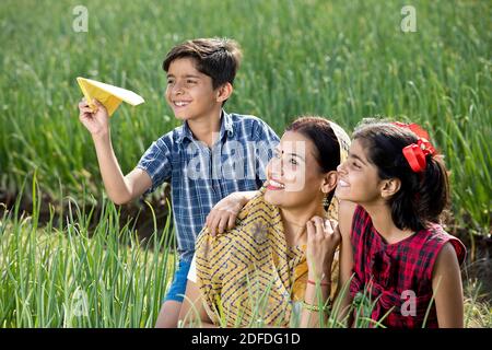 Ländliche Familie mit Jungen werfen Papier Flugzeug auf Landwirtschaft Feld Stockfoto