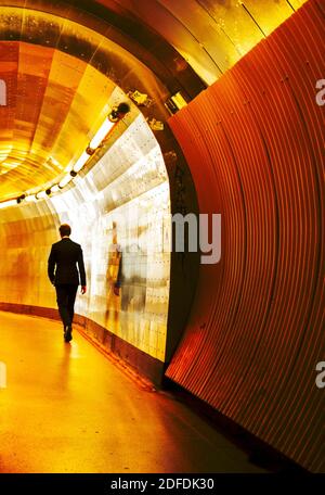 Mann im Geschäftsanzug, der in einem modernen Tunnel hereinläuft Stockholm Stockfoto