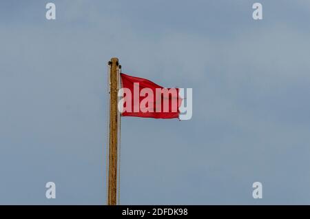 Rote Warnflagge flattert am Himmel Stockfoto