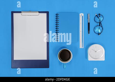 Overhead-Ansicht von Zwischenablage und Büromaterial auf blauem Hintergrund. Stockfoto