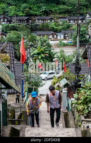 (201204) -- GONGSHAN, 4. Dezember 2020 (Xinhua) -- Kong Dangna (L) geht auf Zementstufen hinauf zum Hügel, um mit ihrem Enkel Li Yongming im Dorf Kongdang der Gemeinde Dulongjiang, Gongshan Dulong und Nu, südwestlich der Provinz Yunnan, Futtergras zu ernten, 31. Oktober 2020. Die 78-jährige Kong Dangna aus der Dulong-Ethnie erlebte einst Jahre mit ungenügender Nahrung und Kleidung und lebte von Brandrost-Anbau. In jenen Tagen dachte sie, das beste Leben sei, Buchweizennudeln für jede Mahlzeit zu essen. Dank der Hilfe der lokalen Regierung, Kongs f Stockfoto