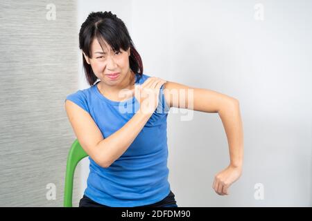 Asiatische Frau mit Schulterschmerzen Stockfoto