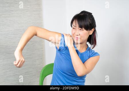 Asiatische Frau mit Schulterschmerzen Stockfoto