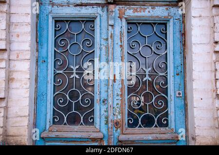 Teil einer blauen Tür aus Holz mit einem Metallgrill im russischen Stil Stockfoto