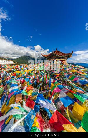 Tibetisch-buddhistische Gebetsfahnen hängen von einer Pagode mit Blick auf die Kawa Garpo Berge, Heimat einer der heiligsten Pilgerfahrten des tibetischen Buddhismus. Stockfoto