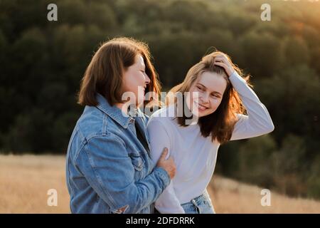 Glückliche Mutter umarmt Tochter während Sonnenuntergang Stockfoto