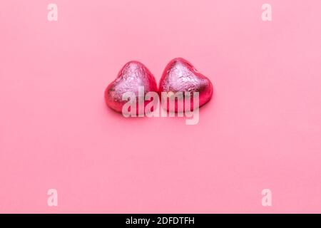 Konzept vom 14. februar oder Valentinstag. Schokoladen Bonbons Herzen in einem rosa Wrapper. Rosa Hintergrund. Speicherplatz kopieren. Stockfoto