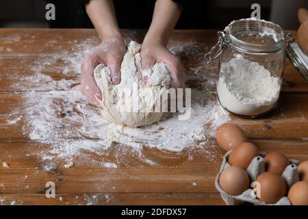 Junge schöne Frau Kneten Teig an einem Holztisch in der Küche. Hausfrau Hobbys Konzept. Stockfoto