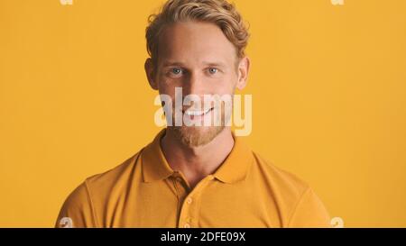 Schöner positiver bärtiger Mann, der glücklich in die Kamera schaut und lächelt Isoliert auf gelbem Hintergrund Stockfoto