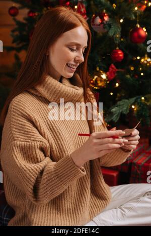 Porträt von verträumten Rotschopf Frau Schreiben Brief an den Weihnachtsmann, Glaube an Weihnachtswunder Stockfoto