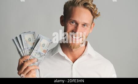 Schöner reicher bärtiger Geschäftsmann mit Geld, das glücklich in die Kamera schaut Und lächelnd isoliert auf weißem Hintergrund Stockfoto
