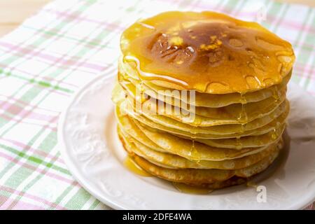 Hausgemachte Pfannkuchen mit Honig auf dem weißen Teller. Zum Frühstück werden hausgemachte Pfannkuchen serviert. Stockfoto