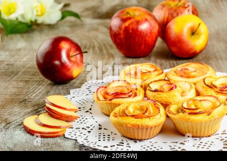 In Form von Rosen Apfel-Muffins auf Holzhintergrund. Süßer Apfel Dessertkuchen. Hausgemachtes Apfelrosengebäck. Stockfoto