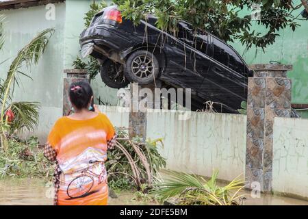 Medan, Nord-Sumatra, Indonesien. Dezember 2020. Eine Frau geht in der Nähe des Wracks eines Autos, das durch die Überschwemmung als Folge des schnellen Flusses, der ihr Haus in Medan untergetaucht wurde, weggefegt wurde. Heftige Regenfälle überschwemmten Tausende von Häusern und ließen eine Reihe von Menschen tot und vermisst. Quelle: Albert Ivan Damanik/ZUMA Wire/Alamy Live News Stockfoto