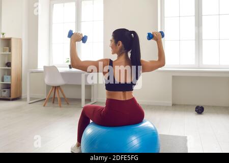 Lächelnd ziemlich junge Fitness schlank weiblich in Sportswear machen Workout Auf fitmess Ball Stockfoto