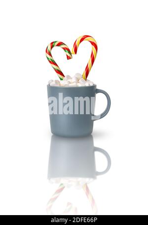 Kakao mit Marshmallows und zwei herzförmigen Candy Stöcke in einer grauen Tasse isoliert auf einem weißen Hintergrund mit Reflexion. Stockfoto