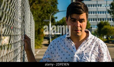 Porträt des realen Lebens Mann, der nach unten schaut, hält Zaun. Stockfoto