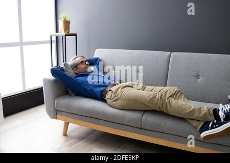 Älterer Mann, Der Sich Auf Dem Sofa Im Wohnzimmer Entspannt Stockfoto
