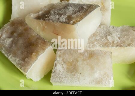 Nahaufnahme der Textur einiger aufgetauter Kabeljaufilets auf grünem Keramikgrund. Tiefkühlkost und Fisch. Stockfoto