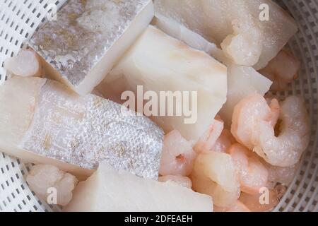 Mehrere frische Kabeljaufilets mit Garnelen auf einem mikroperforierten Kunststoffsieb gemischt. Stockfoto