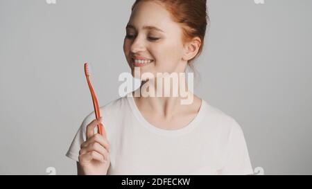 Schönes Mädchen glücklich posiert auf Kamera mit Zahnbürste über weiß Hintergrund Stockfoto