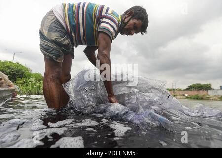 Ein Mann aus Bangladesch wäscht Plastikmüll, der für den Transport von Chemikalien verwendet wurde, im Wasser des Turag-Flusses, bevor er ihn recycelt, in Tongi, in der Nähe von Dhaka, Bangladesch, 9. Juli 2020. Foto von Kanti das Suvra/ABACAPRESS.COM Stockfoto