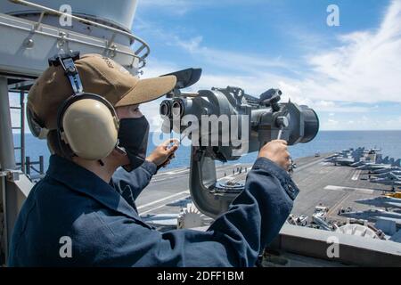 Handout-Foto vom 16. Juli 2020 von Seaman Alexander Chitty, aus Humble, Texas, steht nach vorne Ausschau Uhr auf der Signalbrücke der Navy einzigen nach vorne eingesetzten Flugzeugträger USS Ronald Reagan (CVN 76). Zwei Flugzeugträger der US Navy haben seltene Doppelübungen im Südchinesischen Meer wieder aufgenommen, zum zweiten Mal in diesem Monat haben sich die massiven Kriegsschiffe in den umkämpften Gewässern zusammengetan. Die USS Ronald und USS Nimitz Carrier Streiks Gruppen, bestehend aus mehr als 12,000 US-Militärpersonal unter den beiden Flugzeugträgern und ihre eskortierenden Kreuzer und Zerstörer, waren in der Süd-CH Stockfoto