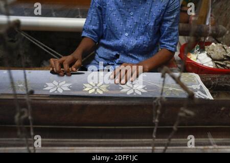 Handwebwebwebweber webt Jamdani Saree auf einem traditionellen hölzernen Handwebwebstuhl in Tarabo, nahe Dhaka, Bangladesch, 18. Juli 2020. Jamdani ist eines der feinsten Musselin-Textilien Bengalens, das seit Jahrhunderten im Dhaka District, Bangladesch, hergestellt wird. Die historische Produktion von jamdani wurde von kaiserlichen Warrants der Mogulherrscher bevormundet. Unter dem britischen Kolonialismus gingen die bengalischen Jamdani- und Musselin-Industrien aufgrund kolonialer Importpolitik, die industriell hergestellte Textilien begünstigte, rasch zurück. In den letzten Jahren hat die Produktion von Jamdani eine Wiederbelebung in Bangladesch erlebt. Das traditionelle Stockfoto