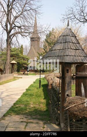 Gasse im Dorfmuseum in Bukarest, Rumänien. Holztor aus dem 19. Jahrhundert aus Alba (Vordergrund) und Kirche aus dem 18. Jahrhundert aus Maramures (Rückseite) Stockfoto