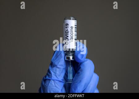 COVID-19 Impfstoffflasche und Spritze für Coronavirus-Heilung in den behandelten Händen des Arztes Nahaufnahme. Konzept der Corona-Virus-Behandlung, Impfstoffinjektion, Nachrichten Stockfoto