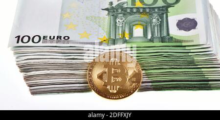 Ein Haufen von 10,000 Euro in hundert 100 Euro Banknoten und ein Bitcoin auf weißem Hintergrund isoliert Stockfoto