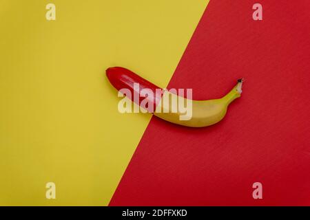 Halbe rote Banane auf zweifarbigem Hintergrund. Flach liegend. Minimales Lebensmittelkonzept Stockfoto