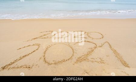 Foto des kommenden neuen Jahres 2021 Text und verlassen Jahr Von 2020 von Lettering Text am Strand mit Welle Und weißer Meeresschaum Zahlen 2021 Jahr auf der Meeresasche Stockfoto