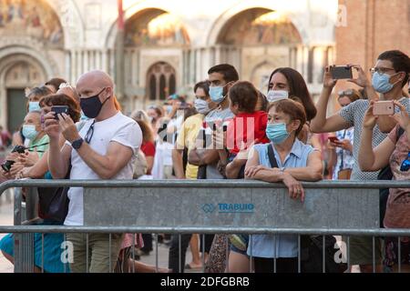 Touristen mit sanitären Gesichtsmasken besuchen doges Stadt während der Coronavirus-Krise. Für Einheimische, die an die geschätzten 30 Millionen Touristen gewöhnt sind, die jedes Jahr kommen, deren Anwesenheit es eine Herausforderung macht, die Rialtobrücke zu überqueren oder ein Foto der Seufzerbrücke zu machen, fühlt sich die Stadt leer an. Sichtbar vermisst werden Besucher aus den USA und China, unter anderem aus anderen Ländern, denen die Reise ins Land noch immer untersagt ist. Obwohl die Besucher auf dem Markusplatz inzwischen über den Tauben und Möwen liegen und die Hotelkapazität 40 bis 50 Prozent beträgt, hat die Stadt laut Bürgermeister noch nicht erreicht Stockfoto